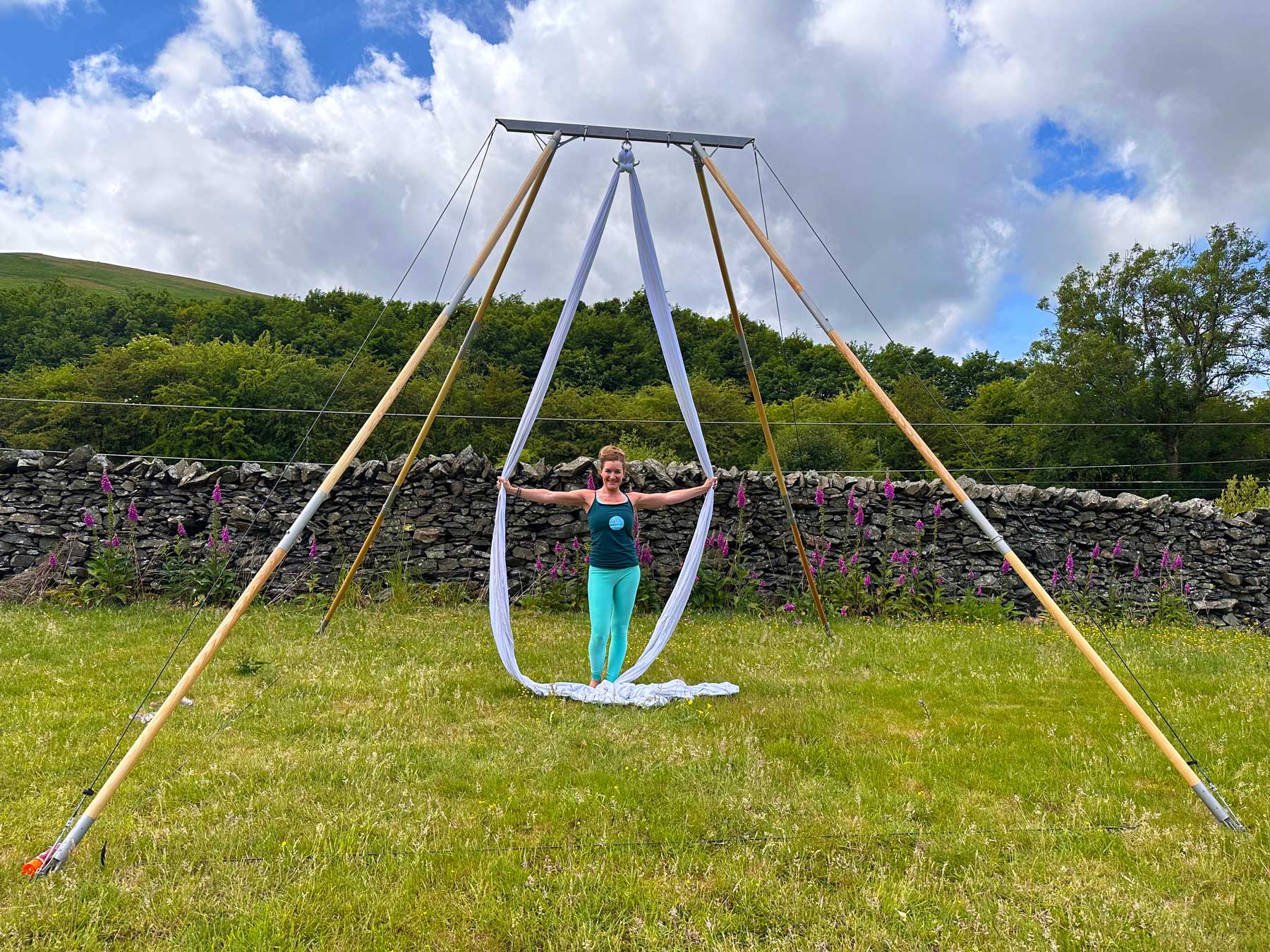 Debbie is in a countryside field demonstrating the Air Frame Large with silks.