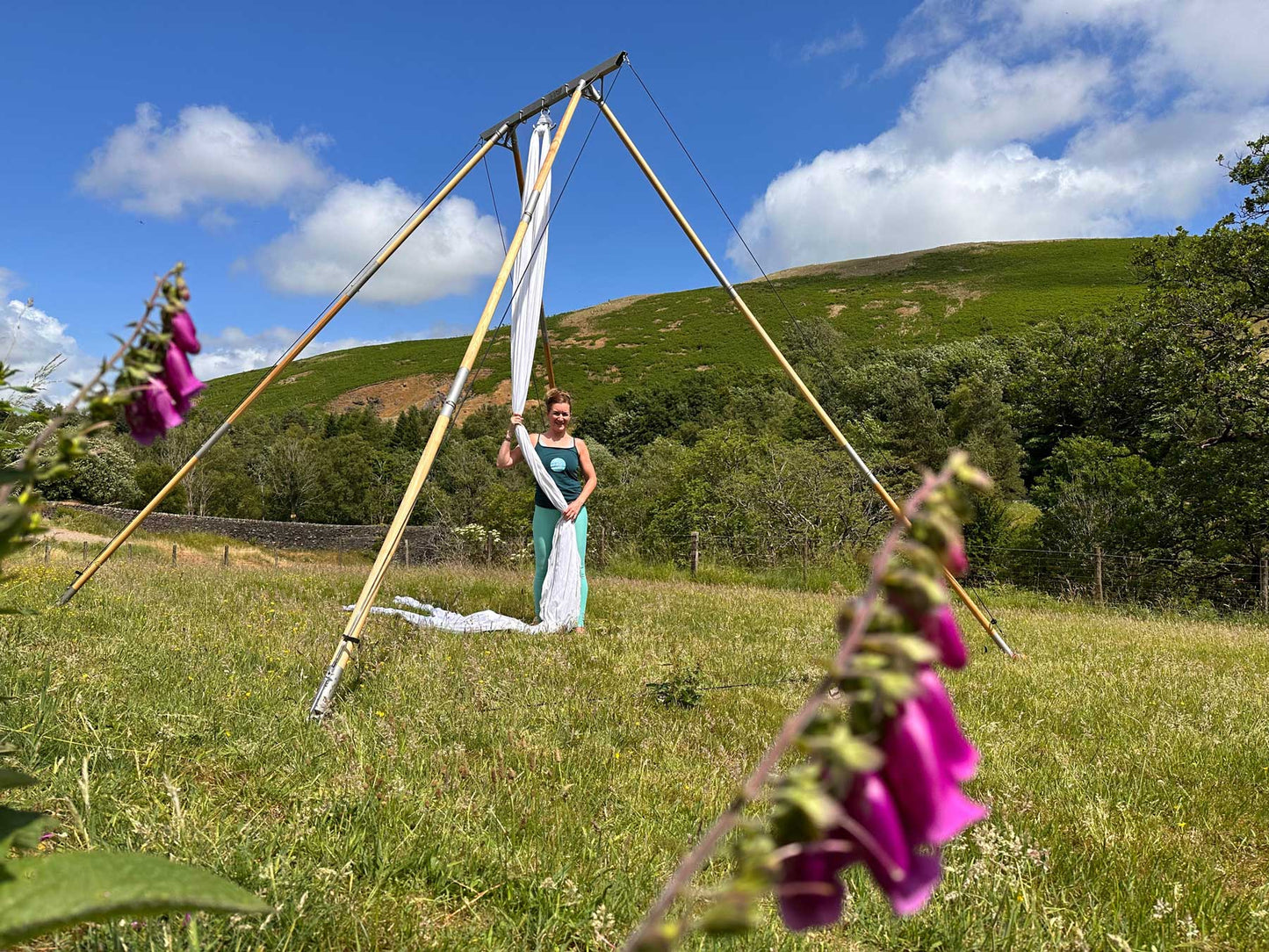 Debbie is in a countryside field demonstrating the Air Frame Large with silks.